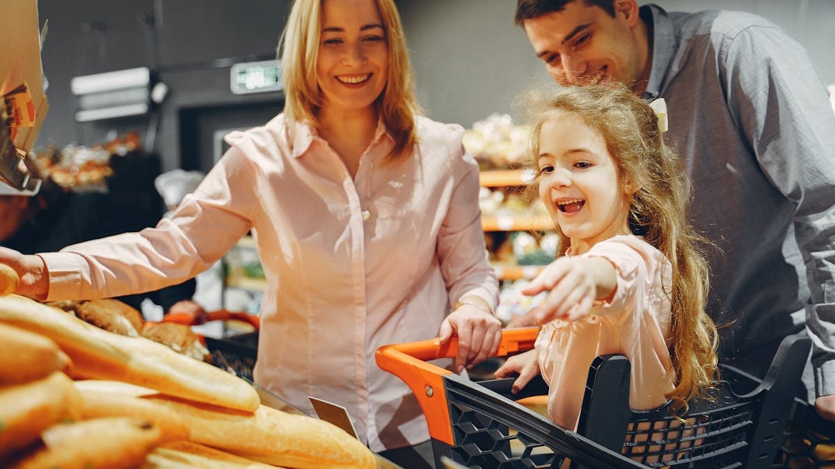 Happy family with a child shopping in a supermarket, smiling and bonding.